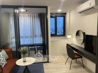 Modern living room with stylish decor and enclosed balcony, featuring a cozy workspace and air conditioning.