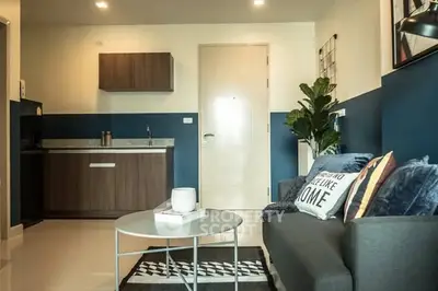 Modern living room with stylish decor and compact kitchen in open layout apartment.