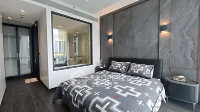 Modern bedroom with stylish decor and large window offering natural light.