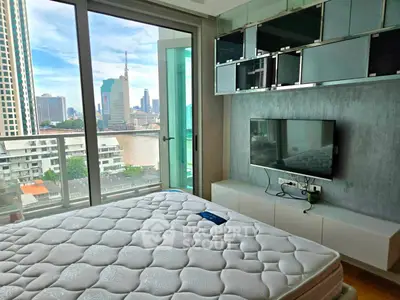 Modern bedroom with city view, featuring sleek furniture and large windows for natural light.