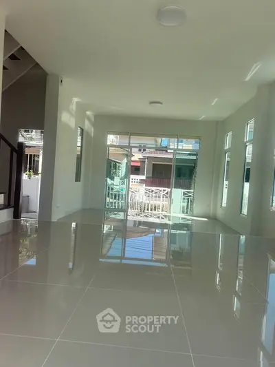Spacious modern living room with glossy tiled floors and large windows offering abundant natural light.