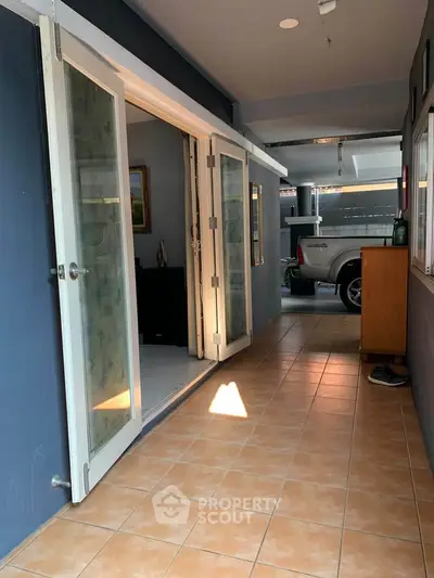 Spacious tiled hallway with glass doors leading to a garage area, perfect for modern living.