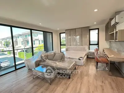Spacious modern living room with large windows and stylish furniture, offering a bright and inviting atmosphere.