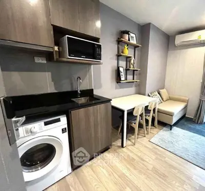 Modern compact kitchen with washing machine and cozy dining area in stylish apartment.