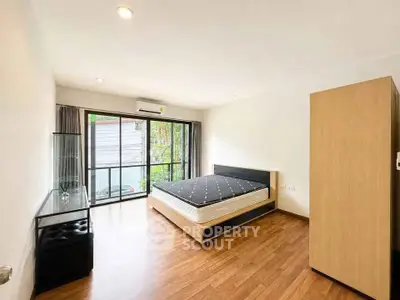Spacious bedroom with modern furnishings and large window offering natural light.