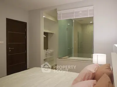 Modern bedroom with ensuite bathroom featuring glass shower and cozy decor.