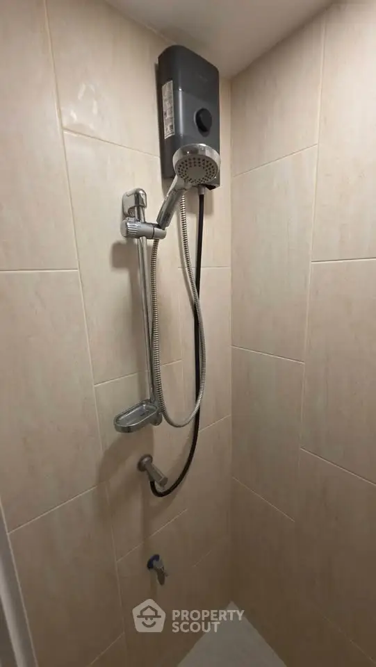 Compact bathroom shower area with modern water heater and tiled walls.