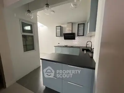 Modern kitchen with sleek cabinetry and open layout, featuring stylish pendant lighting and contemporary design.