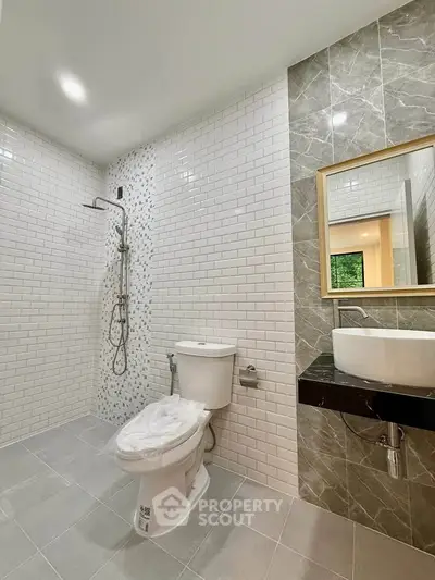 Modern bathroom with sleek design, featuring a shower, toilet, and stylish sink area.