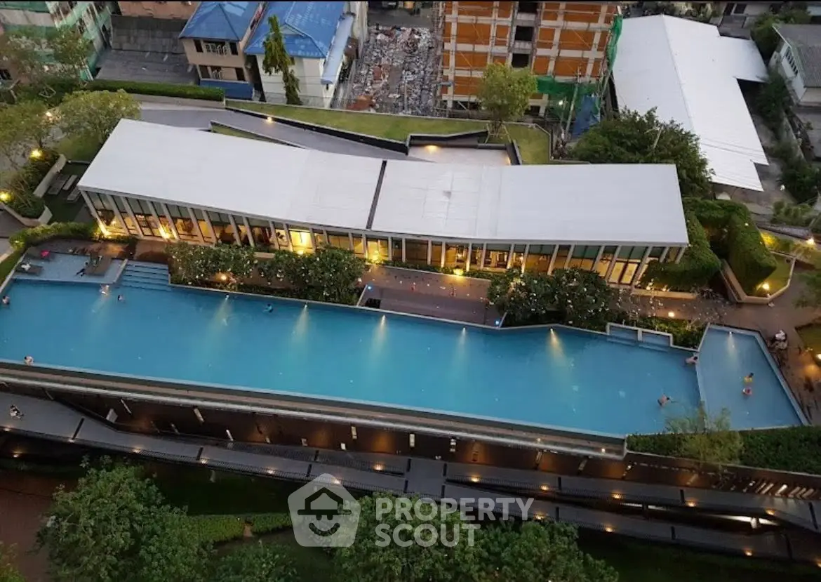 Stunning aerial view of modern building with expansive pool and lush greenery.