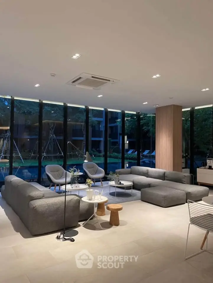 Spacious modern living room with large windows and stylish furniture overlooking a serene garden view.