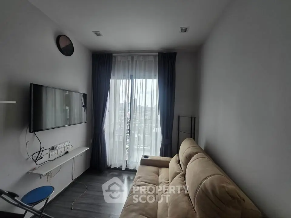 Cozy living room with modern sofa and wall-mounted TV, featuring large window for natural light.