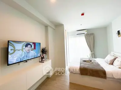 Modern bedroom with wall-mounted TV and cozy decor in a bright apartment.