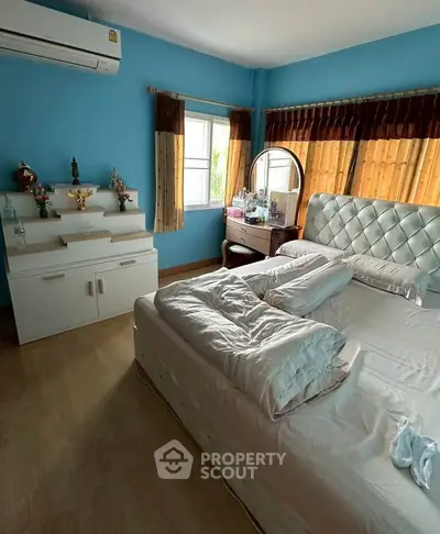Cozy bedroom with blue walls, elegant headboard, and ample natural light.