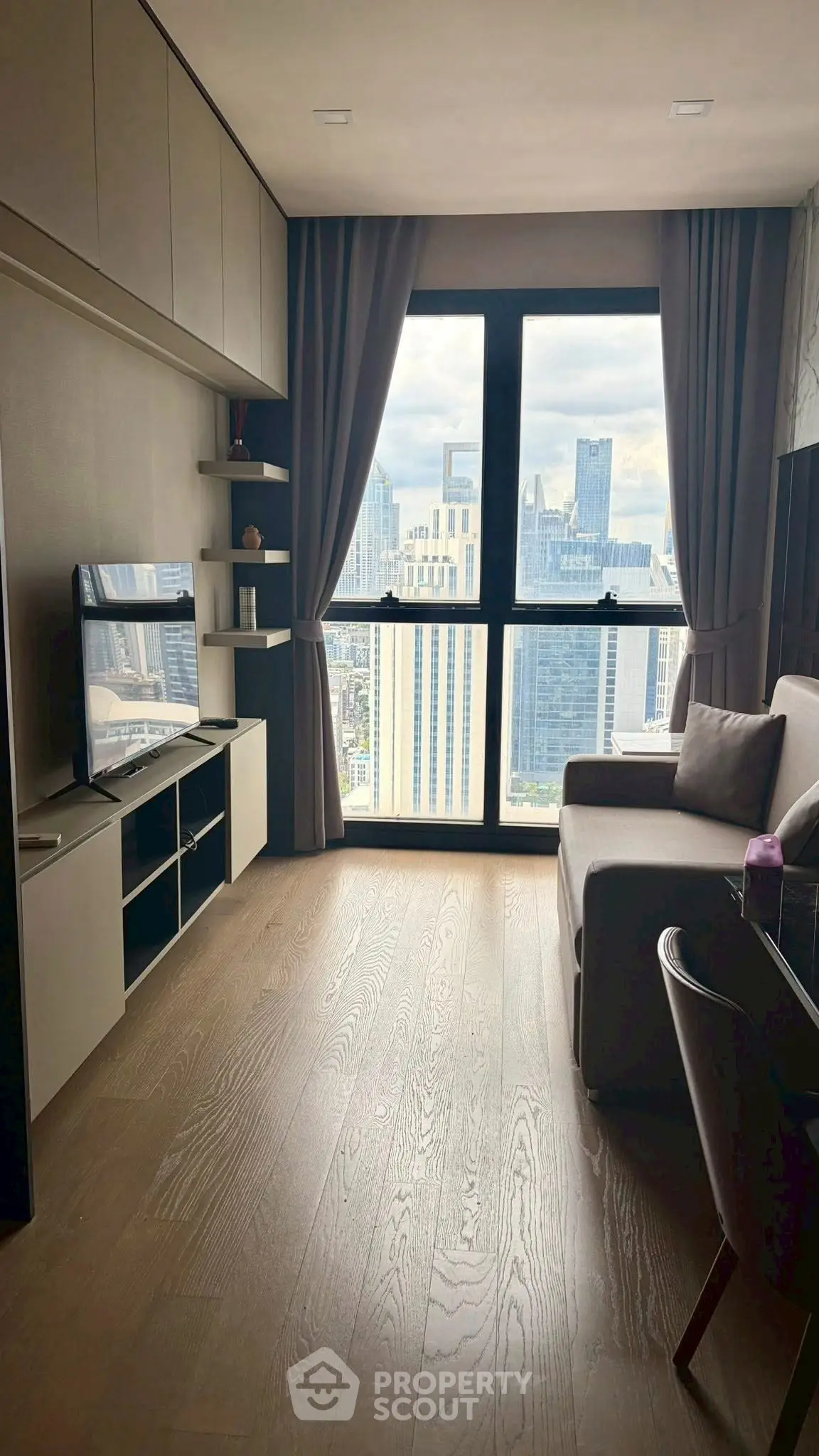 Modern living room with stunning city view, featuring sleek furniture and large windows.