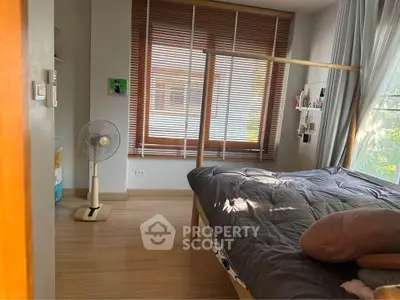 Cozy bedroom with natural light and wooden flooring, featuring a stylish bed and modern decor.