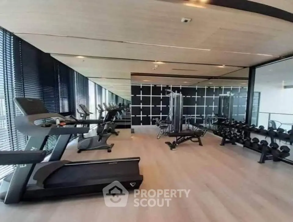 Modern gym with state-of-the-art equipment and mirrored walls in luxury building.