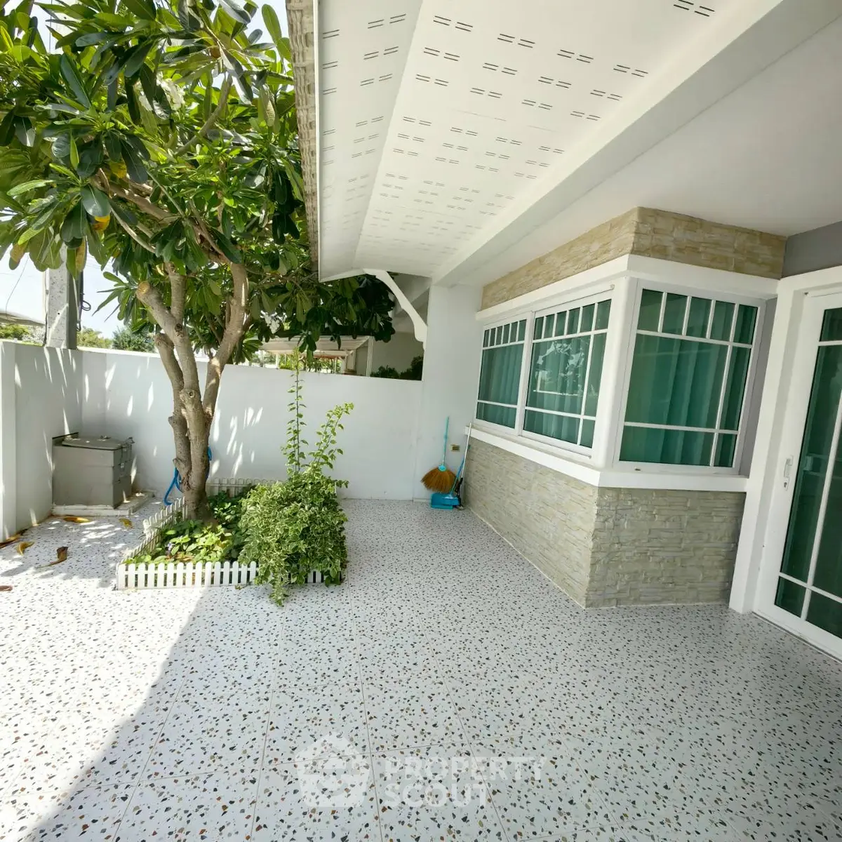 Charming patio with tiled flooring and lush greenery, perfect for outdoor relaxation.