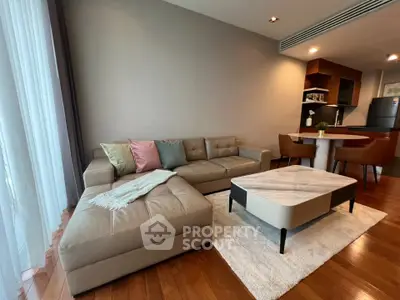 Modern living room with stylish furniture and open kitchen layout, featuring a cozy sofa and elegant dining area.