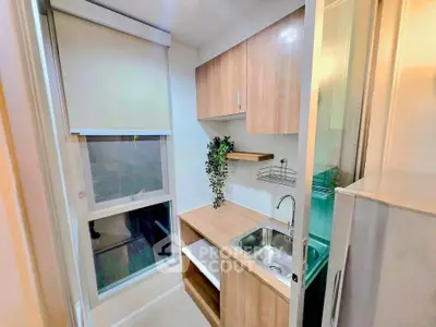 Modern compact kitchen with wooden cabinets and large window, perfect for urban living.