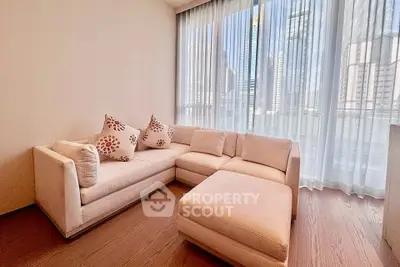Spacious living room with modern sectional sofa and city view through large windows.
