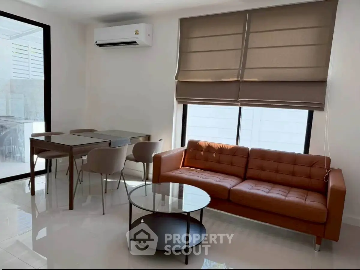 Modern living room with sleek furniture and natural light, featuring a stylish sofa and dining area.