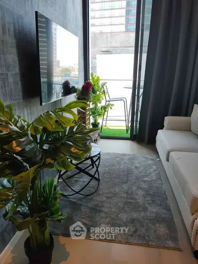 Modern living room with balcony view, stylish decor, and large TV.