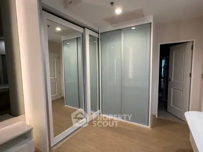 Modern bedroom with sliding mirrored closet doors and wooden flooring