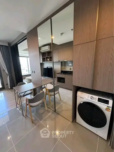 Modern open-layout kitchen with integrated appliances and dining area in stylish apartment.