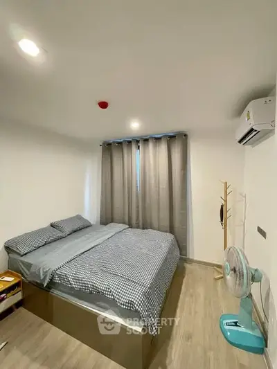 Cozy bedroom with modern decor and natural light, featuring a comfortable bed and air conditioning.
