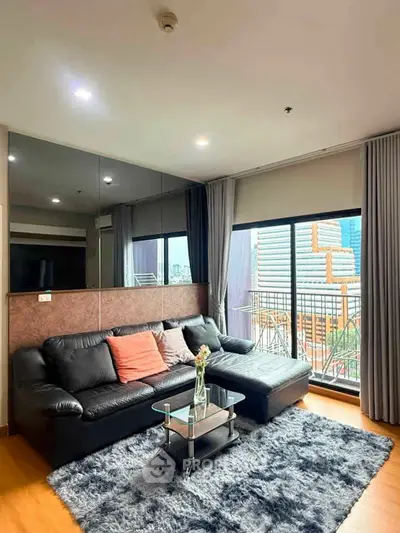 Stylish living room with modern black sofa, glass coffee table, and city view balcony.