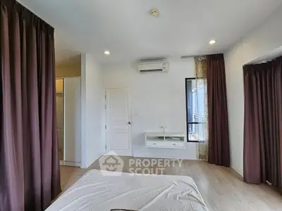 Spacious bedroom with modern decor and large windows for natural light.