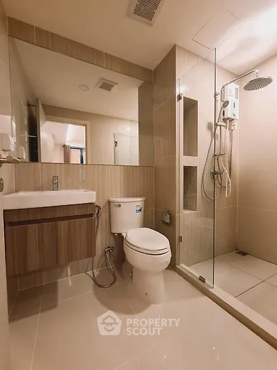 Modern bathroom with glass shower and sleek fixtures in contemporary apartment.