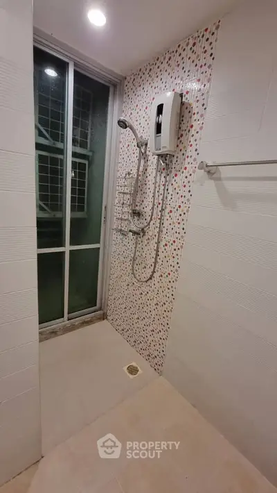 Modern bathroom with shower and sliding glass door, featuring colorful mosaic tiles.