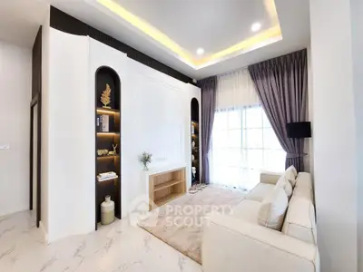 Elegant living room with modern decor, cozy seating, and natural light from large windows.