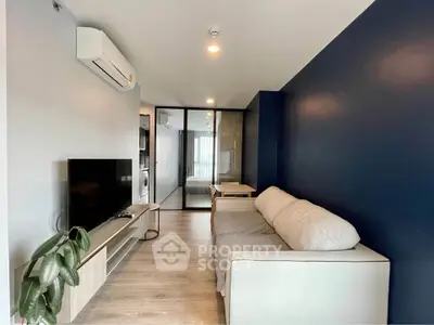 Modern living room with sleek design, featuring a comfortable sofa, flat-screen TV, and stylish blue accent wall.