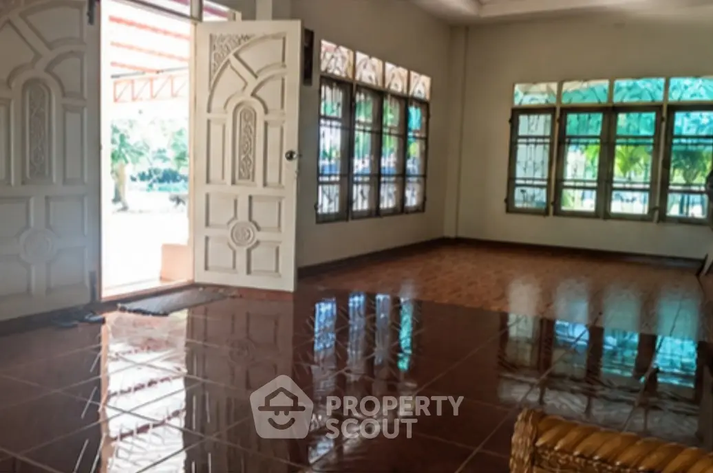 Spacious living room with elegant tiled flooring and large windows offering abundant natural light.