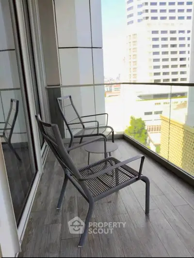 Modern balcony with city view, featuring sleek chairs and glass railing, perfect for urban living.