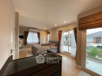 Spacious bedroom with large windows and modern decor in a cozy home.