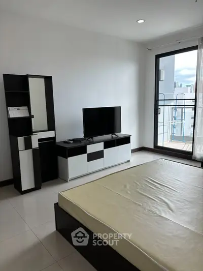 Modern bedroom with balcony access and sleek furniture in a bright apartment.