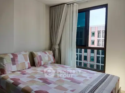 Bright bedroom with modern decor and large window offering city view in a stylish apartment.
