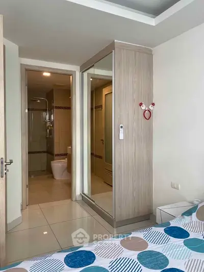 Modern bedroom with ensuite bathroom and mirrored wardrobe in stylish apartment.