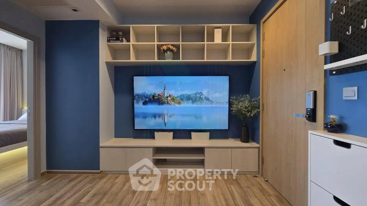 Modern living room with blue walls, wooden flooring, and large TV unit.