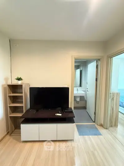 Modern living room with TV and open view to bathroom and bedroom, showcasing sleek design and functionality.