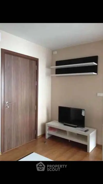 Modern living room with wooden door, TV stand, and wall shelves