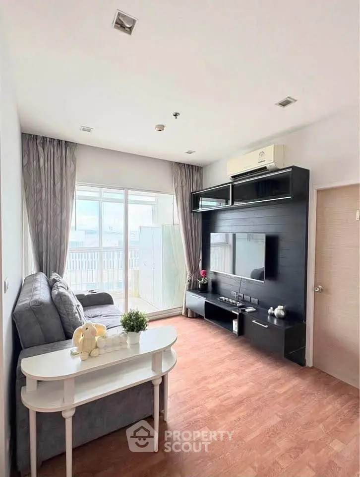 Modern living room with sleek entertainment center and large window leading to balcony.