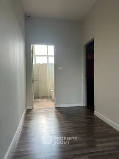 Modern hallway leading to a bright bathroom with sleek flooring.