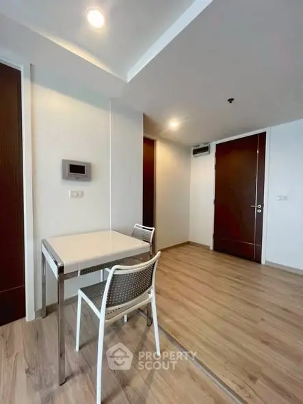 Modern minimalist interior with sleek wooden flooring and compact dining area.