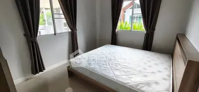 Cozy bedroom with large windows and natural light in modern apartment.