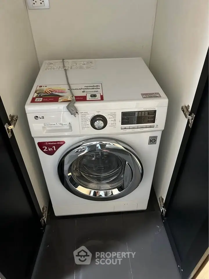 Modern washing machine in sleek laundry nook with glossy floor tiles.